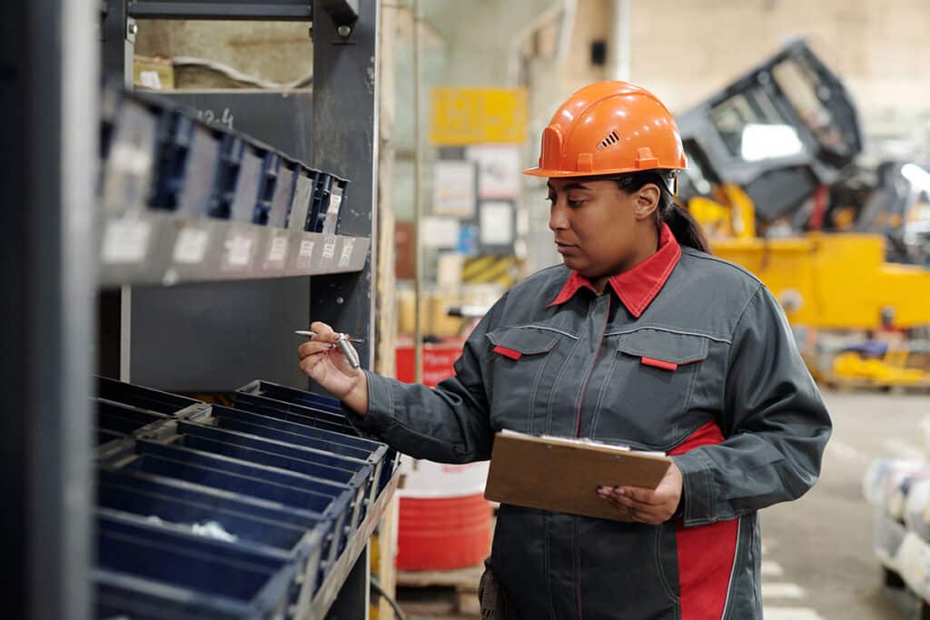 Woman in hard hat selects genuine conveyor parts from a bin